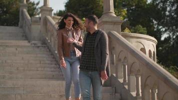 Hübsches junges Paar, das am Herbsttag lächelt und spricht, während es die Außentreppe hinuntergeht? video