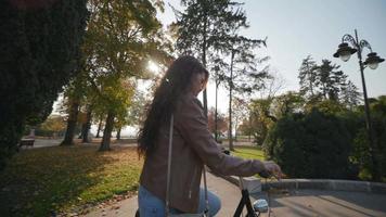 Pretty young woman riding a bicycle in the autumn park video