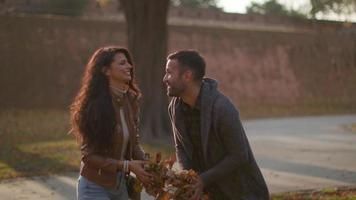Happy young couple having fun with autumn leaves in the park video