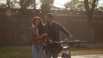 bella giovane coppia che cammina con la bicicletta nel parco autunnale video