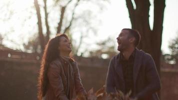 Happy young couple having fun with autumn leaves in the park video