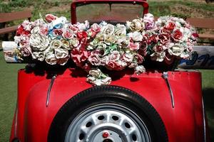 Classic old style of red car decorated by bunch of fake fabric flowers. photo