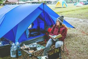 las mujeres asiáticas viajan relajarse acampando en las vacaciones. acampar en la montaña. sentarse relajarse leer un libro en la silla. tailandia foto