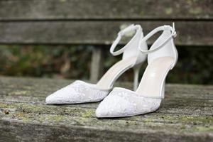 White wedding shoes with lace and heel on old wooden boards photo