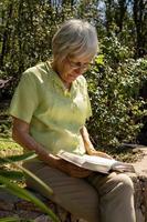 Stylish mature woman reading a book in the garden photo