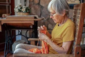 Profile portrait of elderly woman sitting in an armchair at home. photo