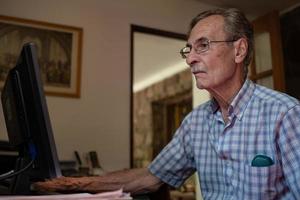 Elderly man using laptop computer. Older man with technology. photo