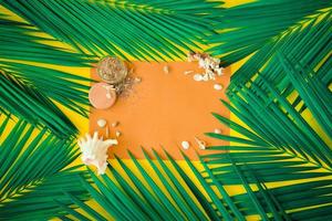 Green tropical palm leaves on bright yellow background. Shellfish and coral implementation format as a table to write postcard messages. Concept art. Summer concept. photo