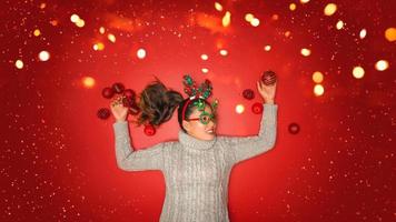 navidad año nuevo. mujer joven vestida con un suéter cálido con apoyos bola roja con adornos navideños en vacaciones sobre fondo rojo brillante. concepto feliz navidad. foto