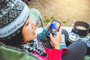 Asian woman travel relax in the holiday. camping on the Mountain. Eating breakfast and sit play the phone. photo