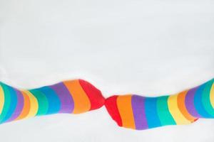 Visibility of LGBTQ community. Two left feet wearing socks with rainbow flag. White background photo