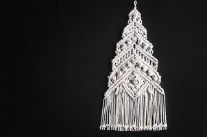 Christmas tree ornament macrame from white natural cotton threads on a black background