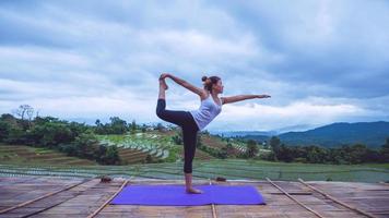 mujer asiática relajarse en las vacaciones. jugar si yoga. en el balcón paisaje campo natural