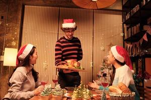 Family's special meal, young male serves roasted turkey to friends, cheerful with drinks and enjoy eating, diner at home's dining room decorated for Christmas festival and New Year celebrations party. photo