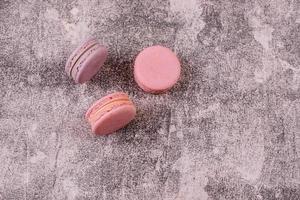 Beautiful pink tasty macaroons on a concrete background photo