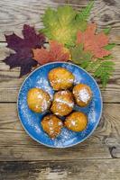 Sweet curd donuts buns with powdered sugar on wooden table
