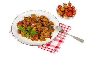 Salteado de verduras de temporada, berenjena con tomates en un plato, bocadillos vegetarianos foto