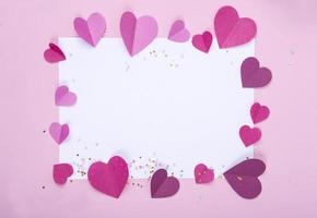 Fondo abstracto con corazones de papel y marco blanco vacío para el día de San Valentín. Fondo rosado de amor y sentimiento para póster, pancarta, postal, tarjeta foto