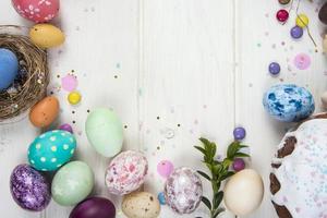 Fondo de colores con huevos de Pascua sobre fondo de tablero de madera blanca. concepto de feliz pascua. se puede utilizar como póster, fondo, tarjeta navideña foto