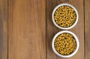 Dry cat food in metal bowl on wooden background. Studio Photo