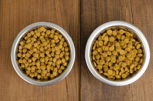 Dry cat food in metal bowl on wooden background. Studio Photo