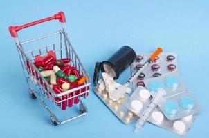 Buy medicine. Shopping basket with various medicinal, pills, tablets on blue background photo