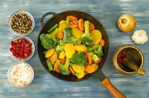 Vegetarian food. Mix of frozen fresh vegetables for frying on blue wooden background. Studio Photo