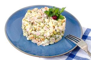 Russian vegetable salad with peas and mayonnaise on blue plate photo