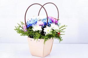 Elegant bouquet of flowers in basket with handles isolated on white background. Studio Photo. photo