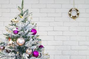 Fragment of decorated Christmas tree on brick wall background. Studio Photo
