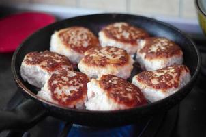 Meat cutlets are fried in pan on stove photo