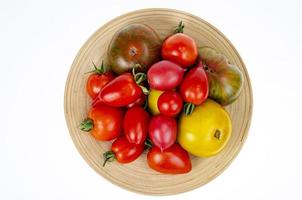 Tomates coloridos caseros surtidos de diferentes formas en placa de madera. foto de estudio.