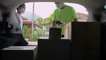 Delivery man wearing face mask handling cardboard box to a teen customer at home.