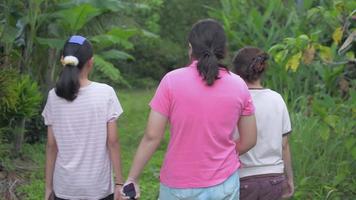Drei Teenager-Mädchen in lässigen Outfits, die zusammen auf dem Feld spazieren gehen.
