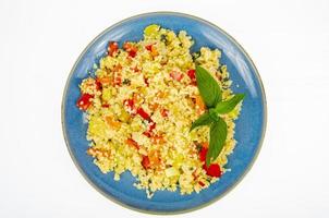 Vegetarian couscous pilaf with vegetables on blue plate. Studio Photo