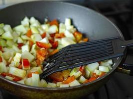 Cubes of fresh vegetables are fried in pan. Studio Photo