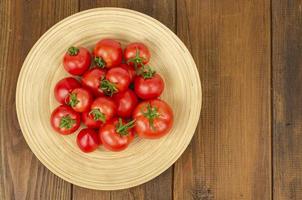 large wooden bamboo dish with ripe tomatoes. Studio Photo.