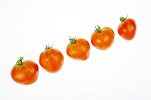 Red tomatoes in shape of heart on white background. Studio Photo