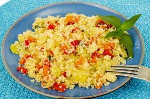 Vegetarian couscous pilaf with vegetables on blue plate. Studio Photo