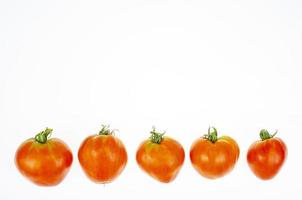 Red tomatoes in shape of heart on white background. Studio Photo