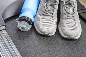 Running track with sneakers and bottle of water on black background. Exercise tools for health. Studio Photo