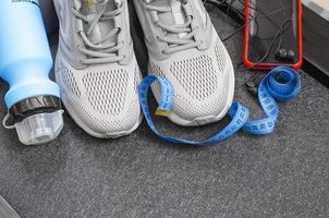 Running track with sneakers and bottle of water on black background. Exercise tools for health. Studio Photo