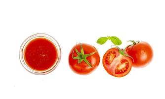Vaso de jugo de tomate natural, tomates rojos frescos sobre fondo blanco. foto