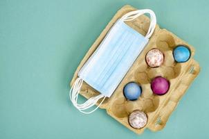 Concept of quarantine at Easter. Decorative eggs and white protective masks on bright background. Social distancing photo