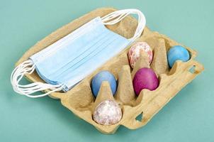 Concept of quarantine at Easter. Decorative eggs and white protective masks on bright background. Social distancing photo