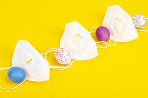 Concept of quarantine at Easter. Decorative eggs and white protective masks on bright background. Social distancing photo