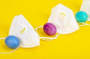 Concept of quarantine at Easter. Decorative eggs and white protective masks on bright background. Social distancing photo