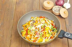 Bright mix of stewed vegetables in frying pan on wooden background photo