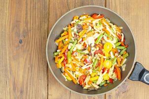 Bright mix of stewed vegetables in frying pan on wooden background photo