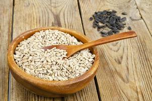 Bowl with sunflower seeds on wooden background. photo